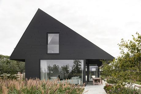 Striking black triangular-roofed structure with expansive glazing and landscaped surroundings.