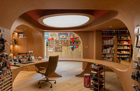 A cozy home office with warm wood tones, curved shelves, and eclectic decor.