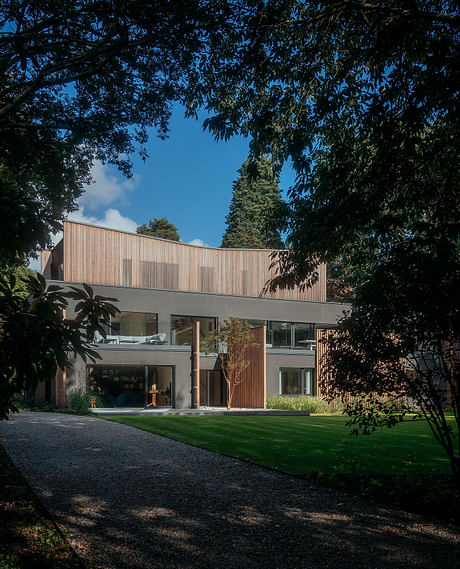 A modern, wood-clad building with large glass windows nestled in a lush, green landscape.