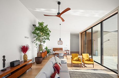 Modern, open-concept living room with large windows, wooden floors, and mid-century furnishings.