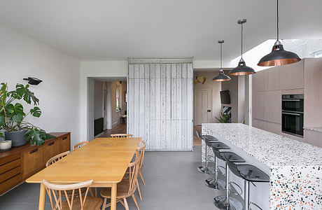 Spacious kitchen and dining area with wooden table, pendants, and terrazzo countertop.