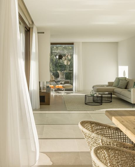 A modern living room with sleek furniture, soft lighting, and large windows overlooking nature.