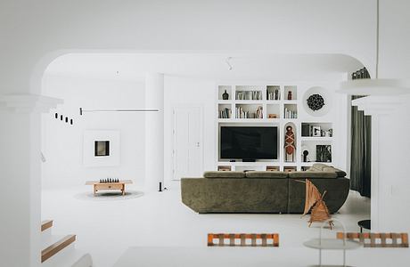 Minimalist living room with built-in shelving, TV, and seating in neutral tones.