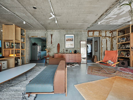 A modern, industrial-style loft with exposed concrete walls, wooden shelving, and vibrant furnishings.