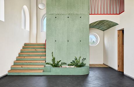 Minimalist interior with green concrete wall, wooden stairs, and various architectural elements.