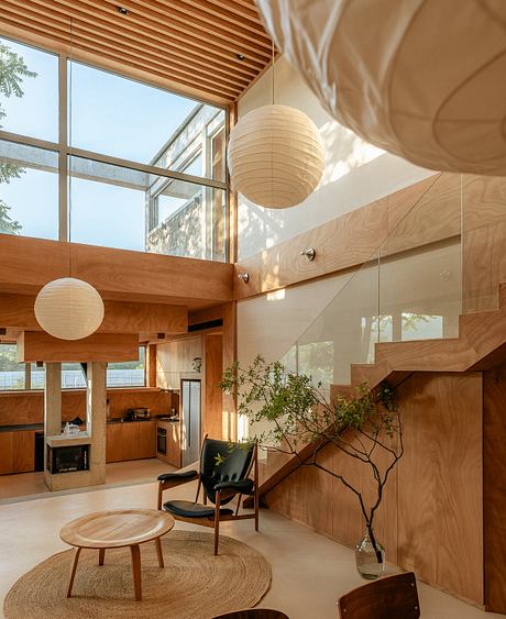 A modern, wood-paneled home interior with minimalist decor, large windows, and paper lanterns.