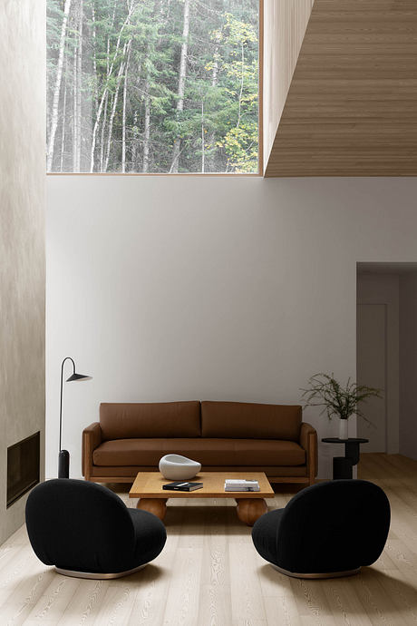 A minimalist living room with a brown leather sofa, black armchairs, and a wooden coffee table, framed by a large window overlooking a forested landscape.
