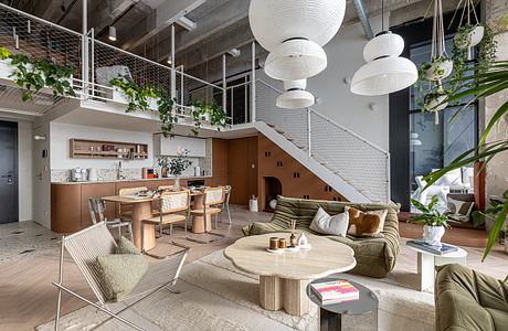 Spacious open-concept living area with hanging plants, white globe lights, and a modern kitchen.