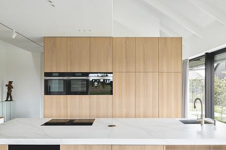 A modern kitchen with a sleek wooden cabinetry, built-in appliances, and a large marble countertop.