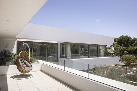 Minimalist modern home design with floor-to-ceiling glass walls and a cozy hanging chair.