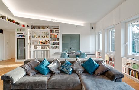 Stylish open-plan living room with built-in shelving, comfortable sofa, and modern decor.