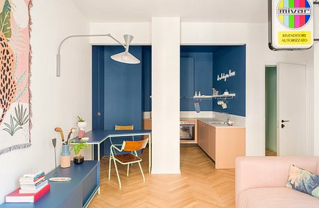 Vibrant, modern apartment with bold blue accents, industrial-style lighting, and cozy furnishings.