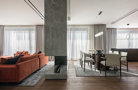 Spacious, contemporary living room with orange sofa, gray marble accent wall, and dining area.