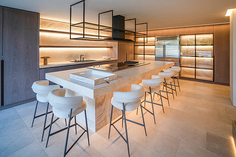 A modern, sleek kitchen with a large island, wood accents, and minimalist lighting.