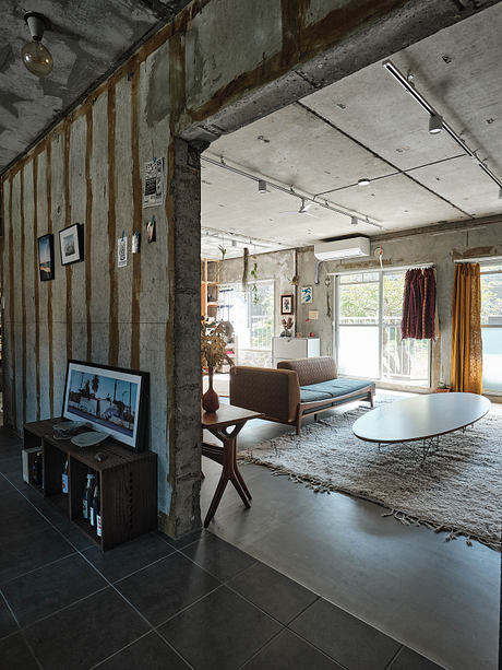 Rustic industrial-inspired interior with exposed concrete walls, wood beams, and modern furnishings.