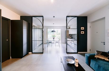 Modern, spacious interior with sleek black-framed glass doors, open-plan layout, and minimalist decor.