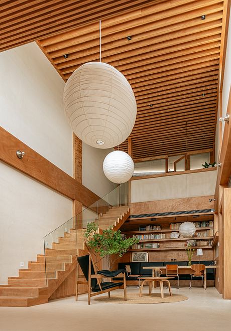 Minimalist interior with wooden slat ceiling, paper lanterns, and built-in bookshelves.