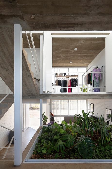 A modern industrial loft with a large indoor garden, exposed concrete, and an open closet space.
