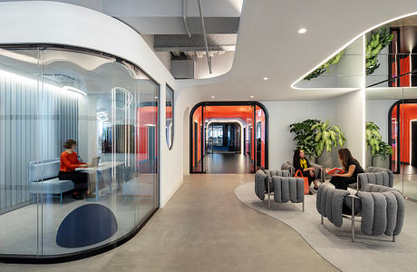 Modern and sleek office interior with glass walls, curved furniture, and vibrant colors.