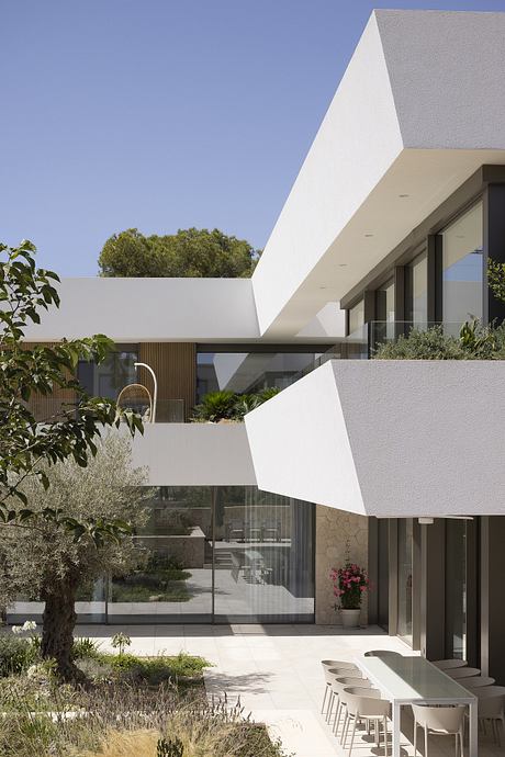 Modern minimalist architectural design with geometric shapes, glass walls, and lush landscaping.