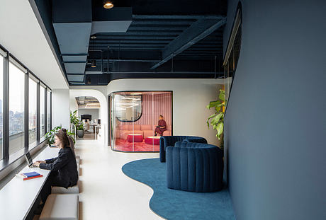A modern, open-plan office space with bold, theatrical design elements and vibrant colors.