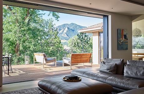 Expansive mountain views framed by sleek indoor-outdoor living space with modern furnishings.