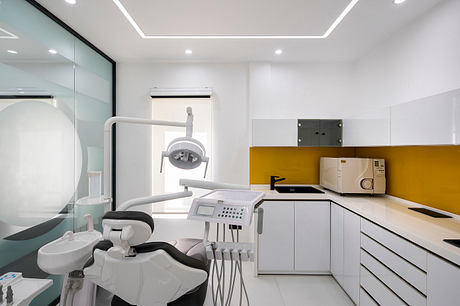 Modern and minimalist dental office with sleek white cabinets, yellow accent wall, and advanced medical equipment.