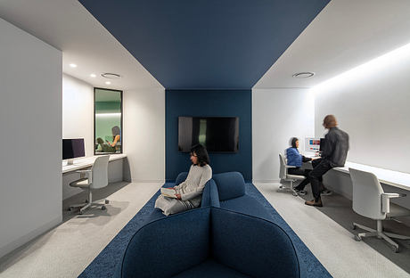 Open-concept office with modern, minimalist design, featuring blue and gray color scheme, comfortable seating, and integrated workstations.