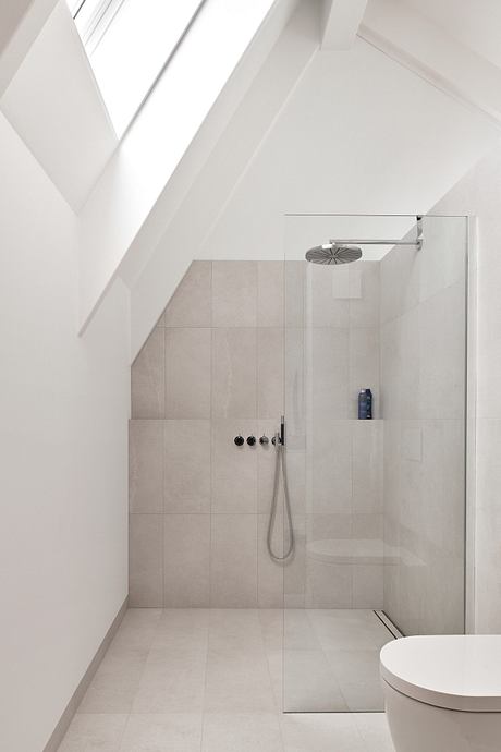 A minimalist bathroom with a sleek, frameless glass shower and textured tile walls.