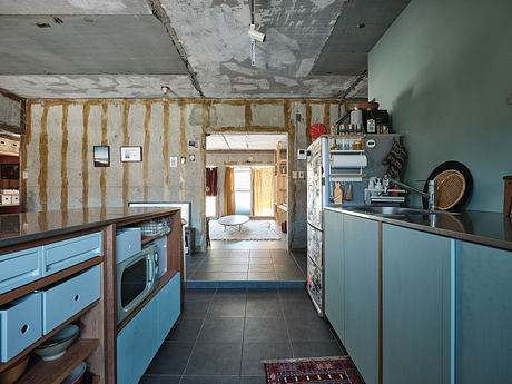A rustic, eclectic kitchen with exposed beams, tiled floors, and blue cabinets.