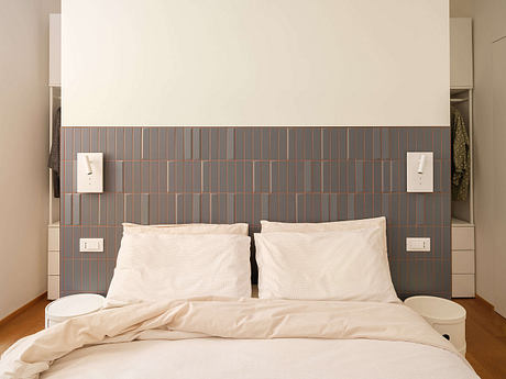 Minimalist bed design with geometric tile wall accent and built-in storage units.