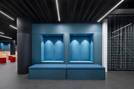 A modern, minimalist interior design with two blue upholstered benches and sleek lighting.