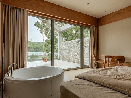 A serene bedroom suite with a deep soaking tub overlooking a wooded exterior.