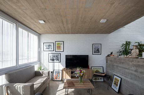 A cozy living room with wooden ceiling, brick walls, and an eclectic mix of furniture and art.