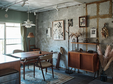 Vintage industrial-style dining area with exposed concrete walls, wooden furnishings, and artwork.