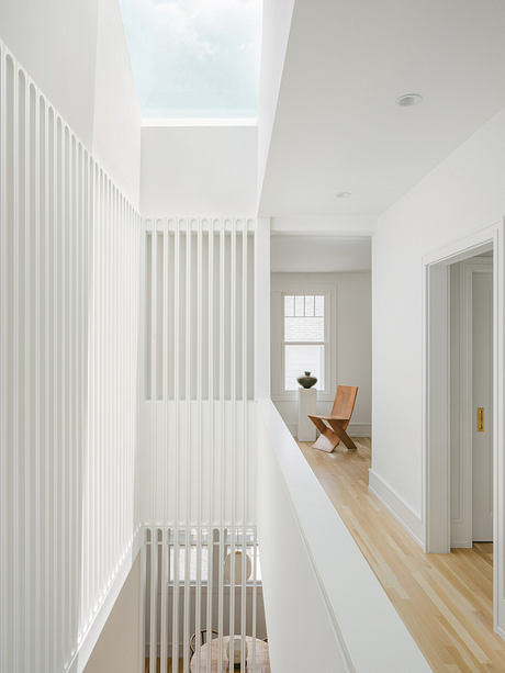 Minimalist hallway with vertical striped walls, wooden floors, and a skylight.