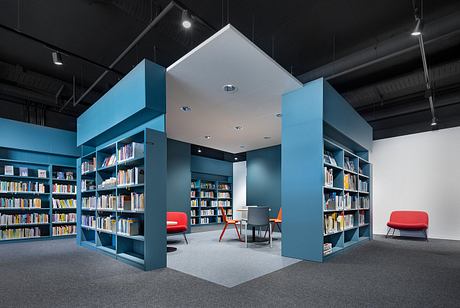 Striking modern library interior with bold blue shelving, geometric shapes, and red accents.