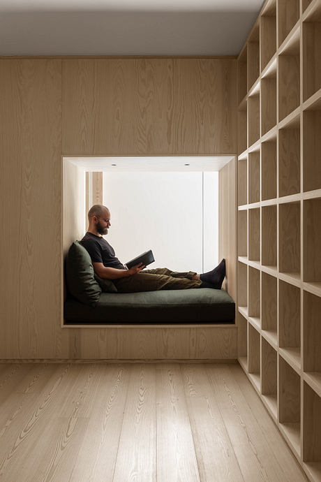 Minimalist built-in bench seating beneath built-in bookshelves in a cozy, wood-paneled nook.