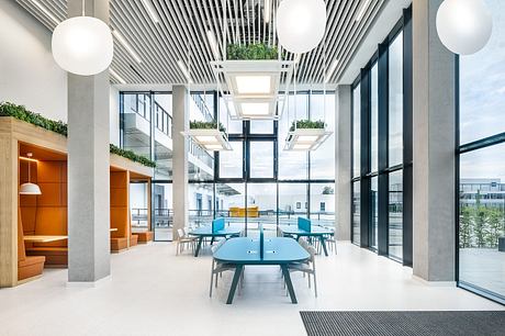 Modern, minimalist office space with geometric ceiling, glass walls, and colorful furniture.