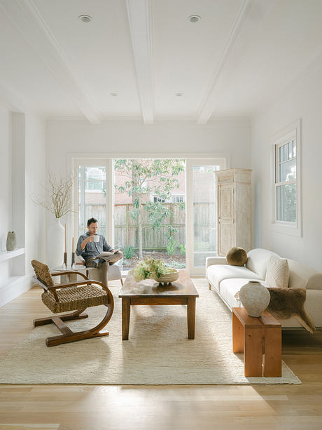 Spacious living room with large windows, wooden furniture, and natural decor elements.