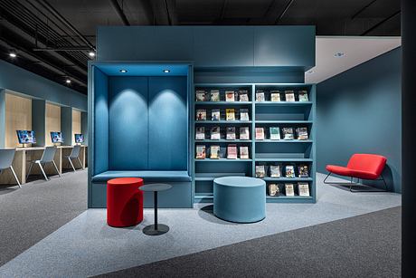 A modern, minimalist office interior featuring a built-in storage unit, comfortable seating, and a bright color scheme.