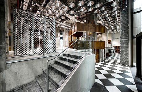 Striking industrial-style interior with geometric lighting, stairs, and patterned flooring.