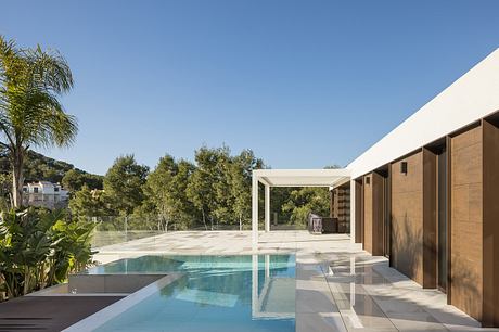 Sleek, modern pool house with minimalist design, glass walls, and lush surrounding.