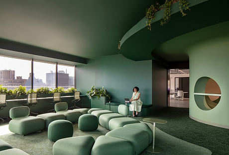 A modern, nature-inspired workspace with lush greenery, curved furniture, and a bold green palette.
