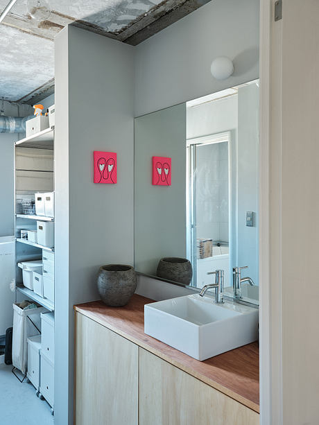 Minimalist bathroom with white sink vanity, wood countertop, and abstract wall decor.