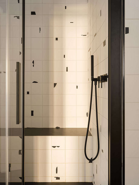 Modern, minimalist bathroom with white tile walls and a black shower fixture.