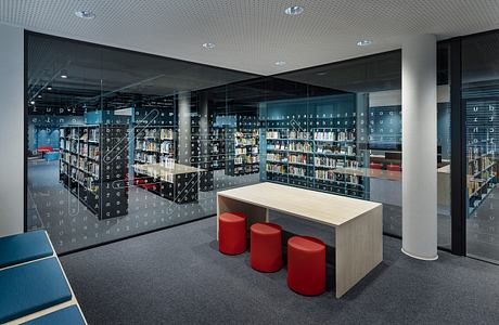 Modern library interior with floor-to-ceiling bookshelves, minimalist furniture, and digital interface.