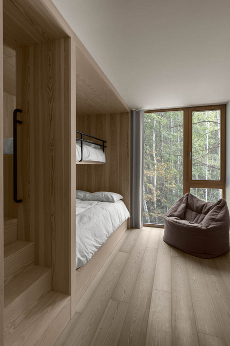 Cozy cabin bedroom with wooden walls, bunk beds, and large window overlooking forest.