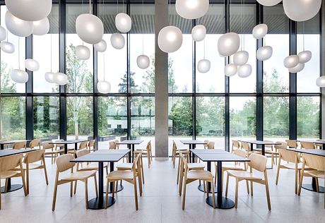 Modern, minimalist interior with floating white orbs, wooden furniture, and large windows overlooking nature.