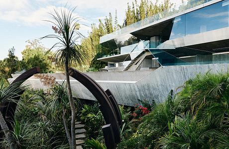 Striking modern architectural design with glass, concrete, and lush vegetation elements.